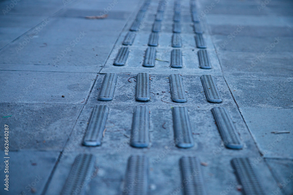 Fototapeta premium Guide path for the visually impaired so they can walk on the pedestrian walkway. Braille blocks, yellow blocks of tactile paving for blind people.