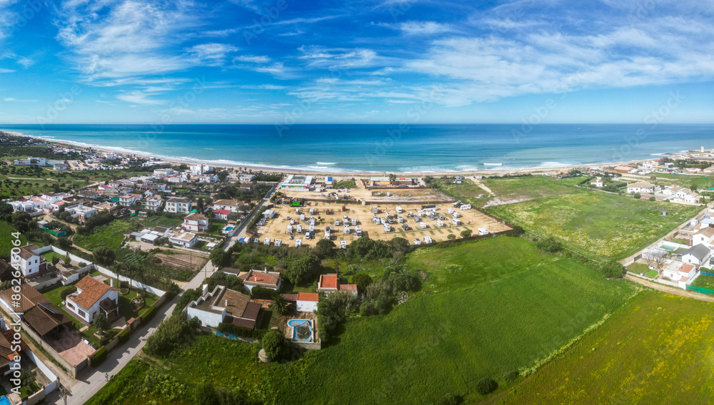 Aerial view of coastal village with beach, sea, and green fields, El Palmar, Cadiz, Spain. Aerial view of coastal village with beach, sea, and green fields, El Palmar, Cadiz, Spain.