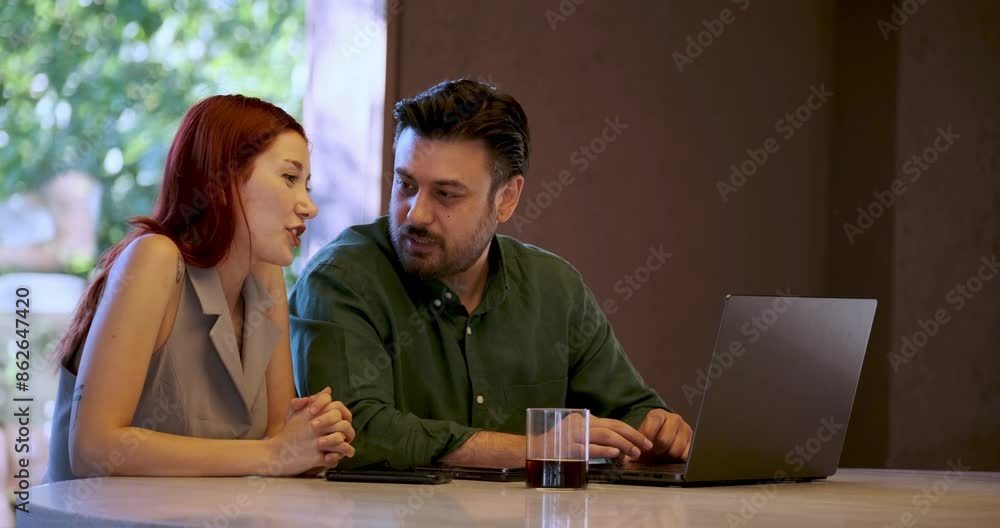 A middle-aged businessman and a young businesswoman are having a pleasant business meeting with their laptops in a cafe outside the office environment A middle-aged businessman and a young businesswoman are having a pleasant business meeting with their laptops in a cafe outside the office environment