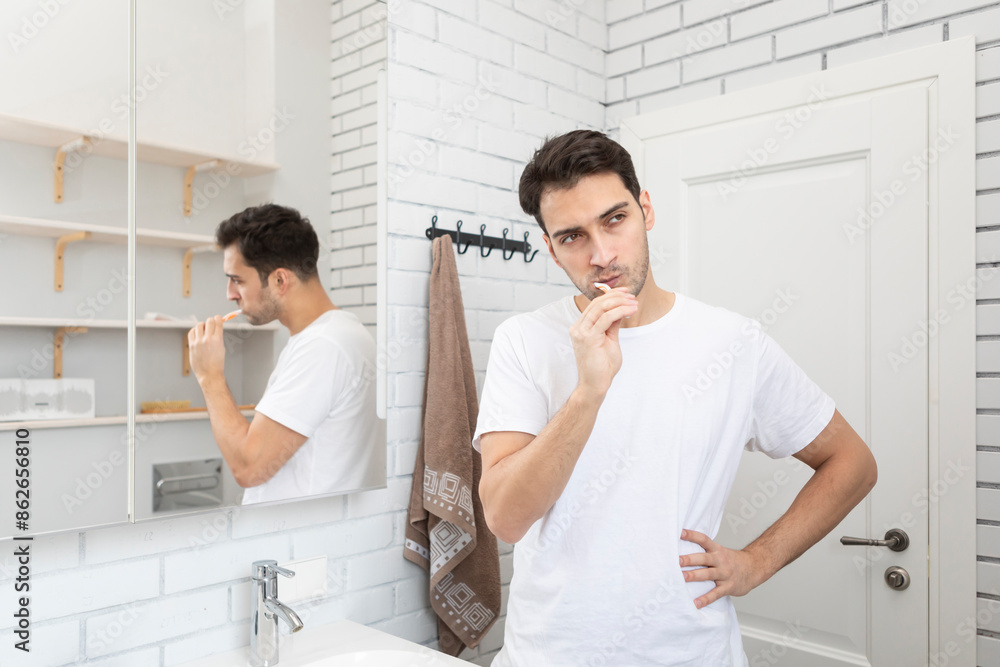 Handsome man brushing teeth in the bathroom Handsome man brushing teeth in the bathroom