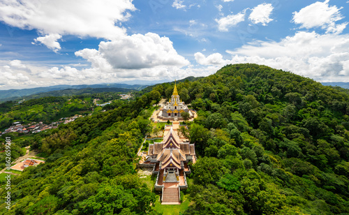 Aerial view of Phrathat Chedi Srinagarindra Stit Maha Santi Khiri Temple surrounded by mountain, forest, and sky, Mae Salong Nok, Thailand. photo