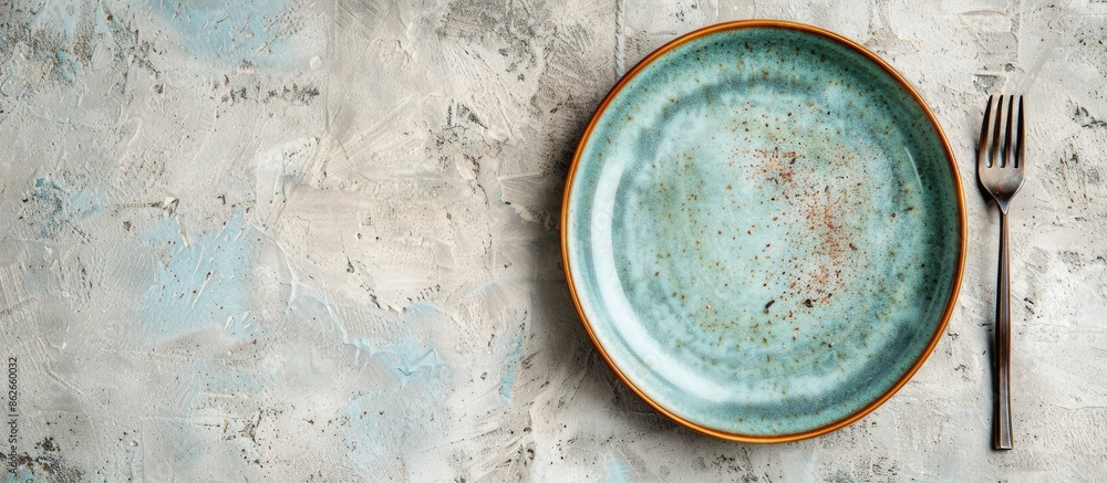Top-down view of ceramic tableware including a plate with a fork on a plain background with space for text or other images. Copy space image. Place for adding text and design Top-down view of ceramic tableware including a plate with a fork on a plain background with space for text or other images. Copy space image. Place for adding text and design