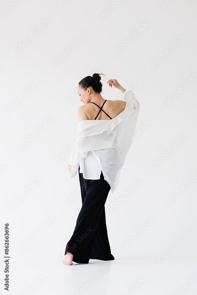 Stylish asian woman posing in black jumpsuit and shirt on grey Stylish asian woman posing in black jumpsuit and shirt on grey