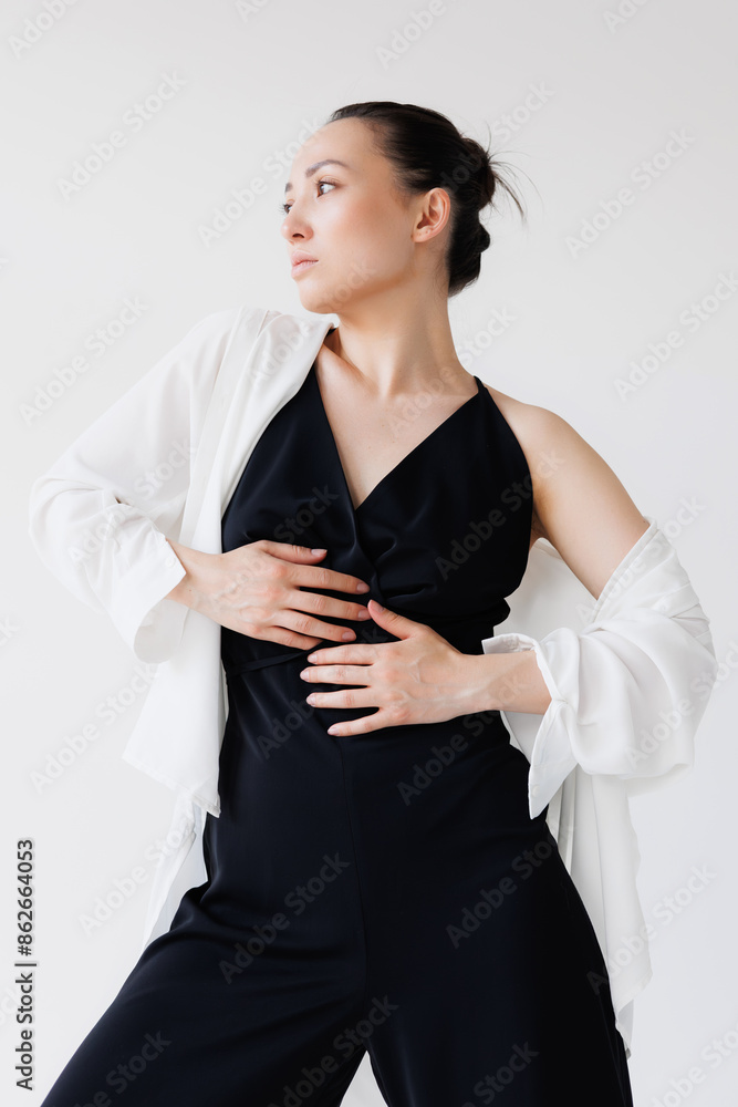 Brunette asian woman in white shirt and jumpsuit posing isolated on grey Brunette asian woman in white shirt and jumpsuit posing isolated on grey