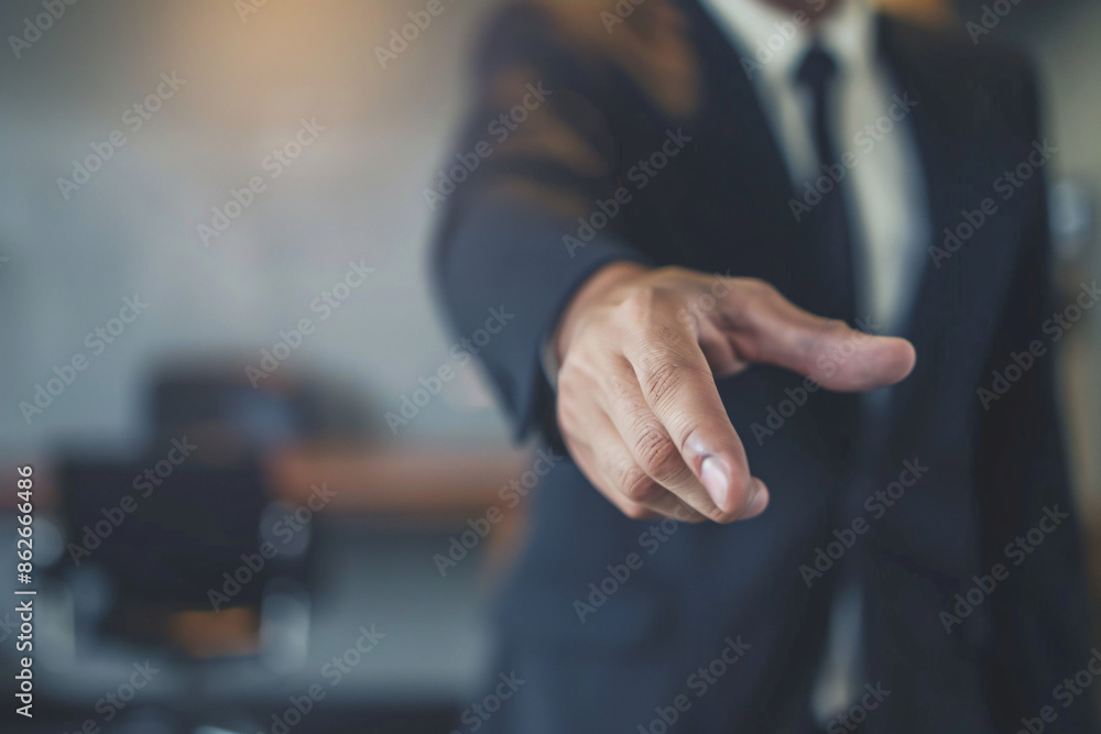A businessman in a suit extending his hand for a handshake in an office setting symbolizing agreement A businessman in a suit extending his hand for a handshake in an office setting symbolizing agreement