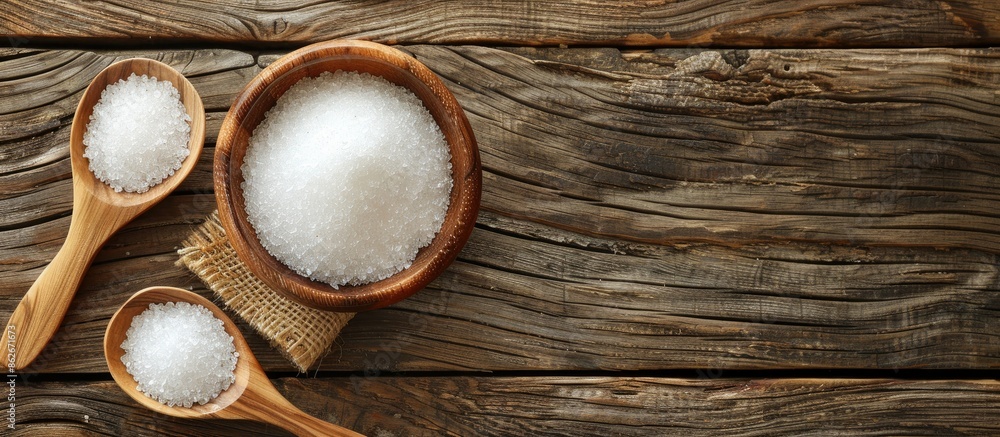 Wooden background hosts a wooden bowl and spoon filled with sugar, perfect for a copy space image. Wooden background hosts a wooden bowl and spoon filled with sugar, perfect for a copy space image.