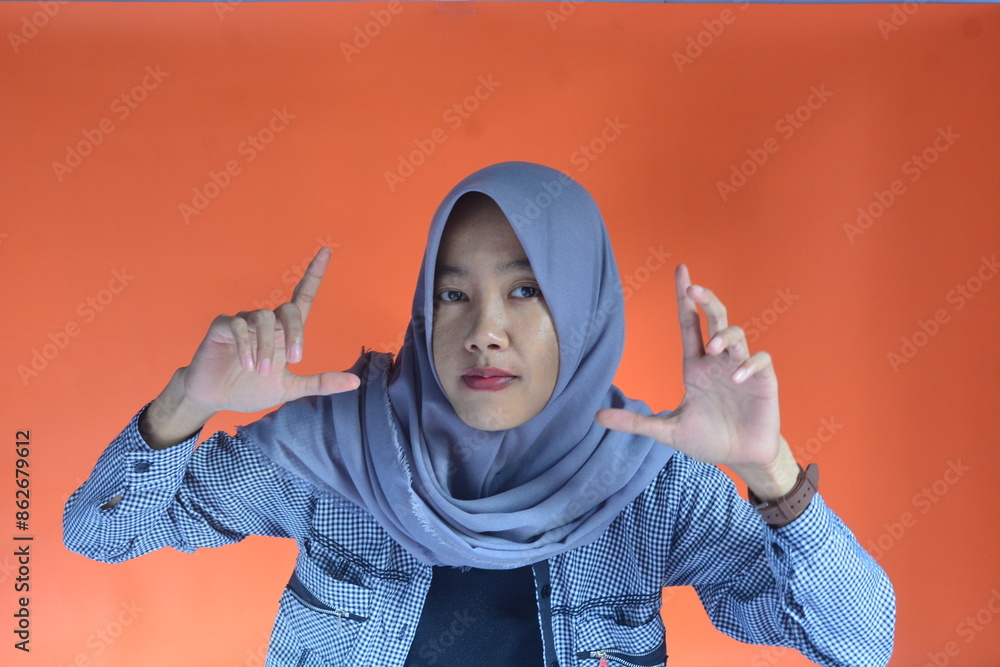 Portrait of an Asian Muslim woman in casual style on an isolated orange background Portrait of an Asian Muslim woman in casual style on an isolated orange background