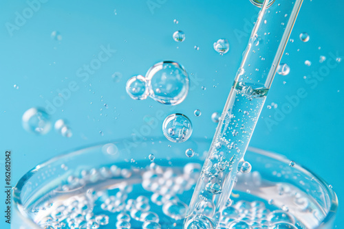 Close up view macro shot of gel with different sized bubbles comes out from lab dropper into petri dish on blue background.