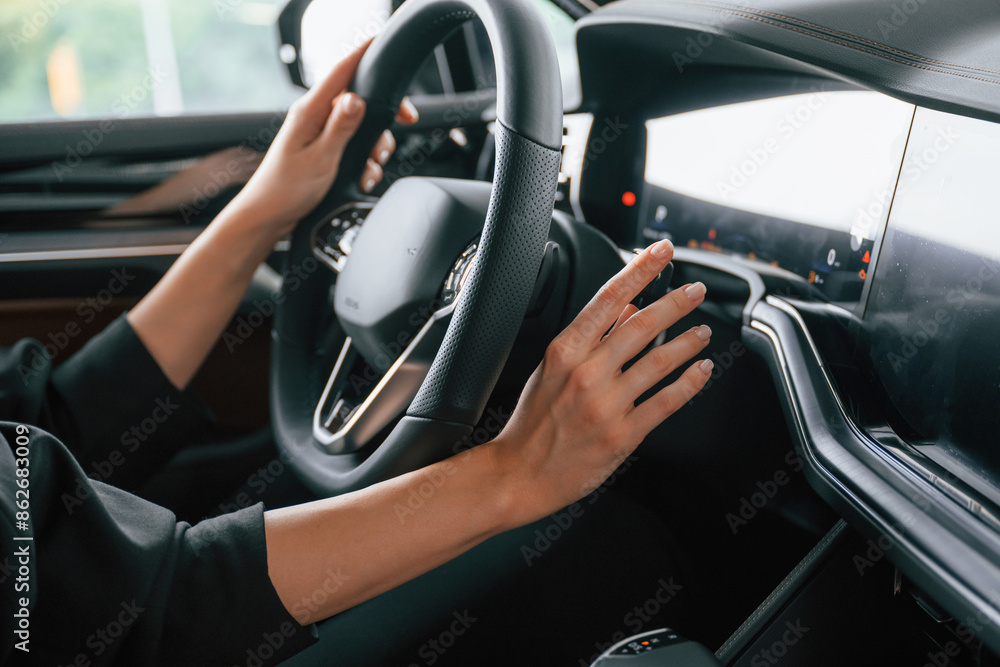 Naklejka premium Focused close up view of woman hands that are driving new car