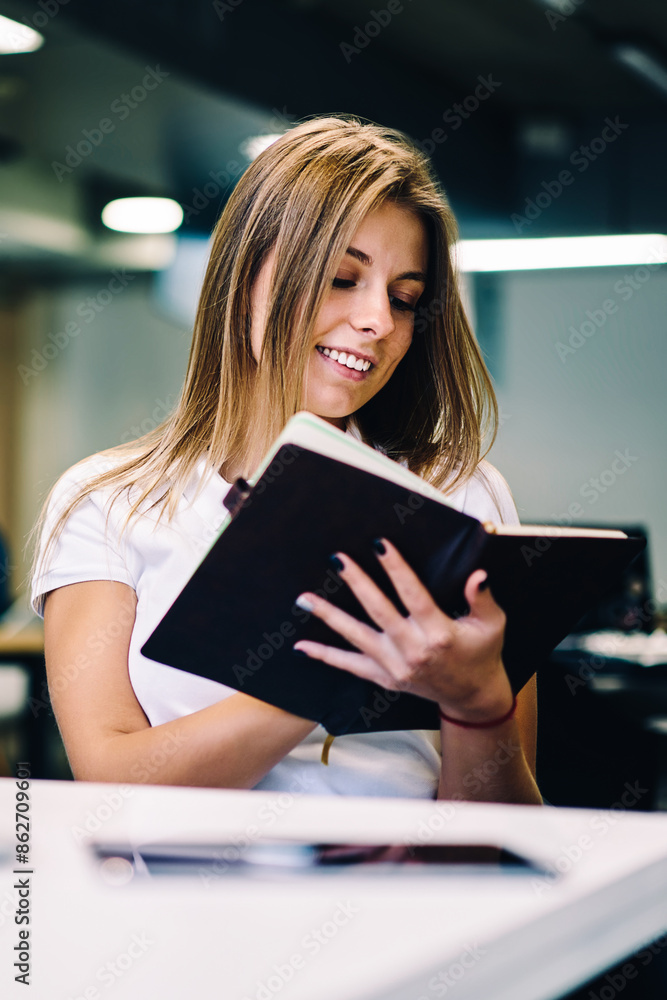 Smiling hipster girl holding notepad checking items in to do list satisfied with completing tasks in planning, cheerful female student writing essay for homework having creative ideas for noting Smiling hipster girl holding notepad checking items in to do list satisfied with completing tasks in planning, cheerful female student writing essay for homework having creative ideas for noting