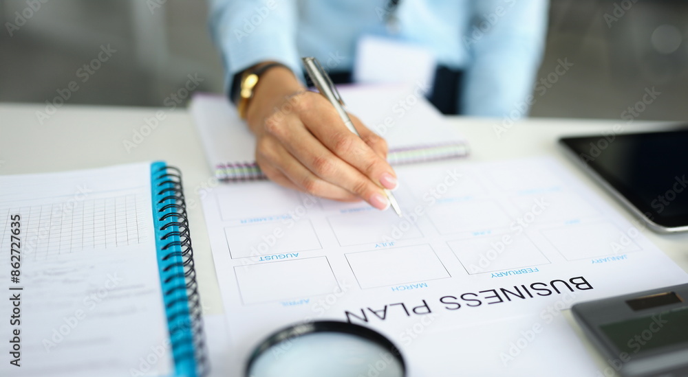 Woman hand holds pen and analyzes business plan. Business planning and statistics concept Woman hand holds pen and analyzes business plan. Business planning and statistics concept