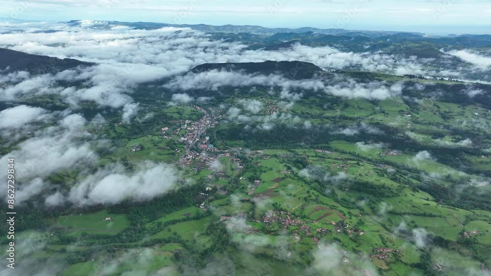 Aerial view of picturesque village nestled in lush green valley with mountain range in Spanish countryside, Asturias, Spain. Aerial view of picturesque village nestled in lush green valley with mountain range in Spanish countryside, Asturias, Spain.