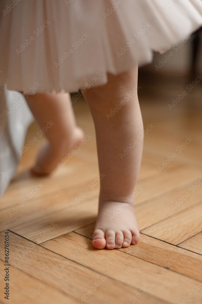 the first steps of a 12 month baby girl on the wooden floor at home the first steps of a 12 month baby girl on the wooden floor at home