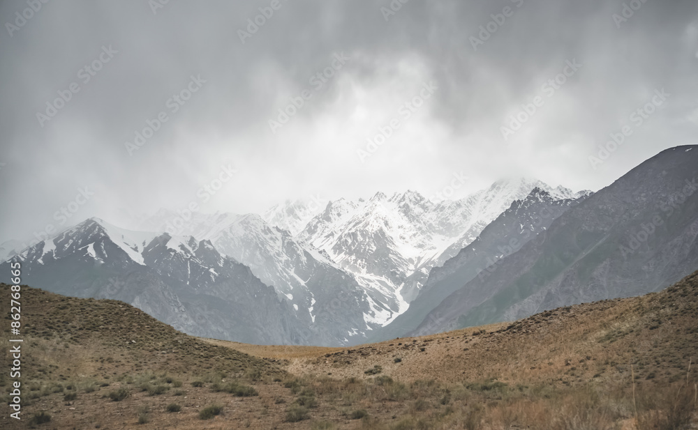 Panorama of mountain range of rocks with snow and glaciers in Pamir in Tajikistan mountains in cloudy weather, minimalistic landscape of high mountains for background Panorama of mountain range of rocks with snow and glaciers in Pamir in Tajikistan mountains in cloudy weather, minimalistic landscape of high mountains for background
