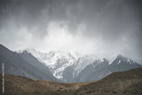Panorama of mountain range of rocks with snow and glaciers in Pamir in Tajikistan mountains in cloudy weather, minimalistic landscape of high mountains for background © Denis