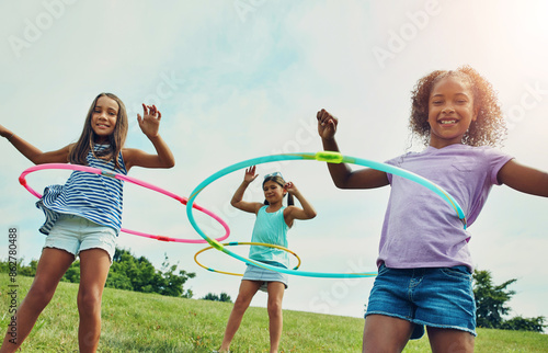 Portrait, hula hoop and kids in park, girls and happiness with fun, bonding together and playful. Childhood, outdoor or friends with recreation, game or cheerful with weekend break, summer or leisure photo