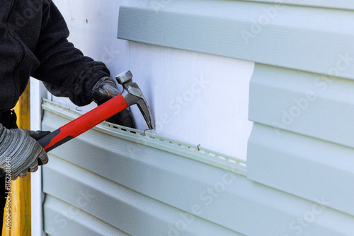 Konstfotografi As part of an exterior house renovation, damaged plastic siding is being replace