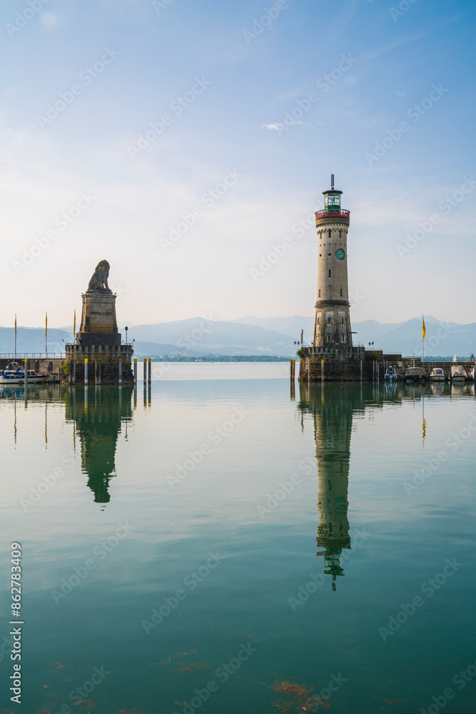 Germany, Lindau island harbor lighthouse view to austrian coast, bregenz city and mountains nature landscape reflecting in silent bodensee lake water early in the morning Germany, Lindau island harbor lighthouse view to austrian coast, bregenz city and mountains nature landscape reflecting in silent bodensee lake water early in the morning