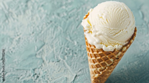 Delicious vanilla ice cream in a waffle cone, with a textured blue background. Perfect for summer and dessert-related concepts.