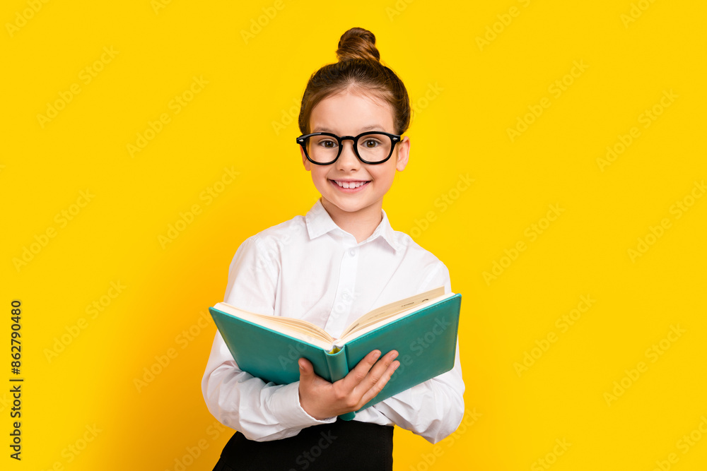 Photo of cute schoolgirl hold opened book wear uniform isolated on yellow color background Photo of cute schoolgirl hold opened book wear uniform isolated on yellow color background