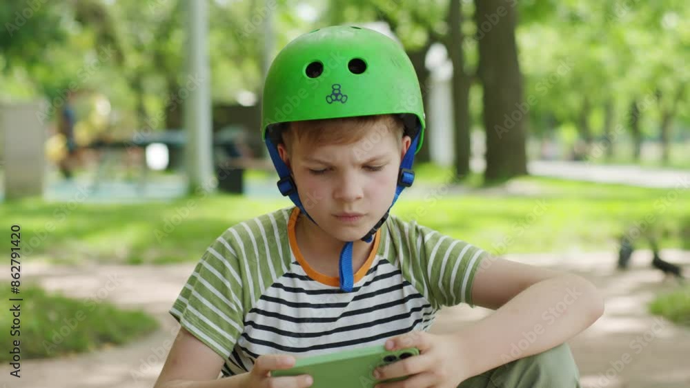 A boy wearing a helmet stands in an urban park, holding his cellphone and looking directly at the camera, blending safety, technology, and outdoor activity A boy wearing a helmet stands in an urban park, holding his cellphone and looking directly at the camera, blending safety, technology, and outdoor activity