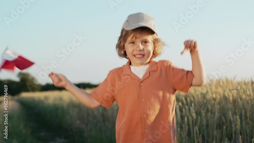 Polish little cute boy, national flag in field. Happy child, Poland national day photo