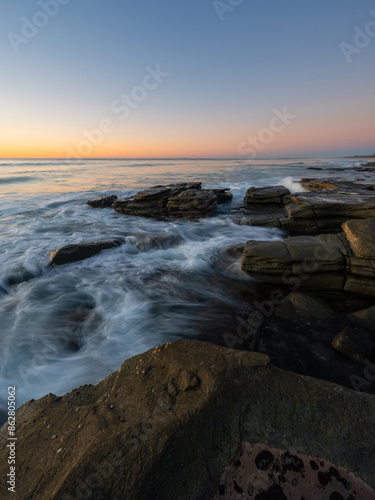 Beautiful morning pastel sky over rocky coastline.