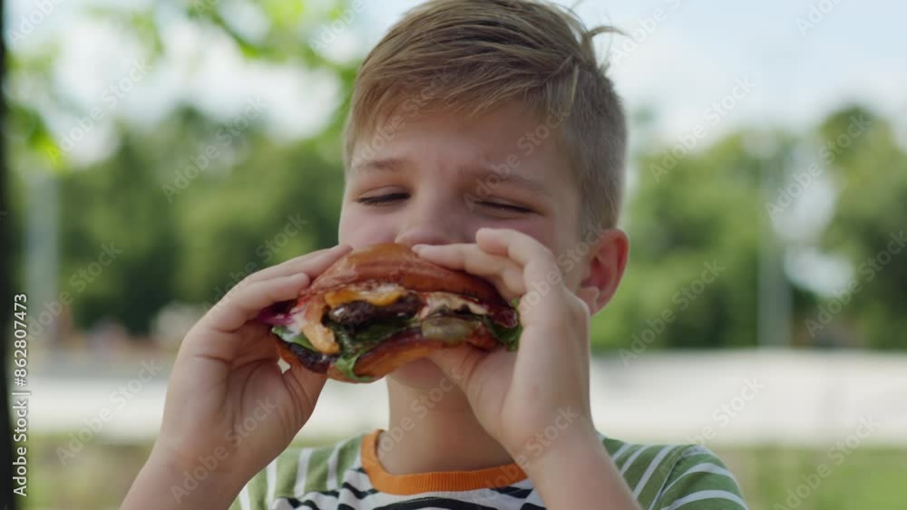In a lively urban park, an 8-year-old kid enjoys a delicious burger, capturing the joy of outdoor eating in a bustling city environment In a lively urban park, an 8-year-old kid enjoys a delicious burger, capturing the joy of outdoor eating in a bustling city environment