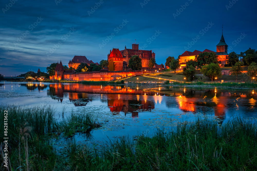Castle of theTeutonic Order in Malbork by the Nogat river at dusk. Castle of theTeutonic Order in Malbork by the Nogat river at dusk.