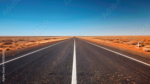 Straight road with white lines in middle of outback red centre Australia