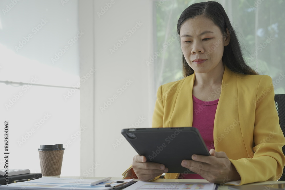 Happy young businesswoman in bright colored shirt uses computer and laptop in modern office Smiling manager while working on finance and marketing project Drink tea or coffee from a glass Happy young businesswoman in bright colored shirt uses computer and laptop in modern office Smiling manager while working on finance and marketing project Drink tea or coffee from a glass