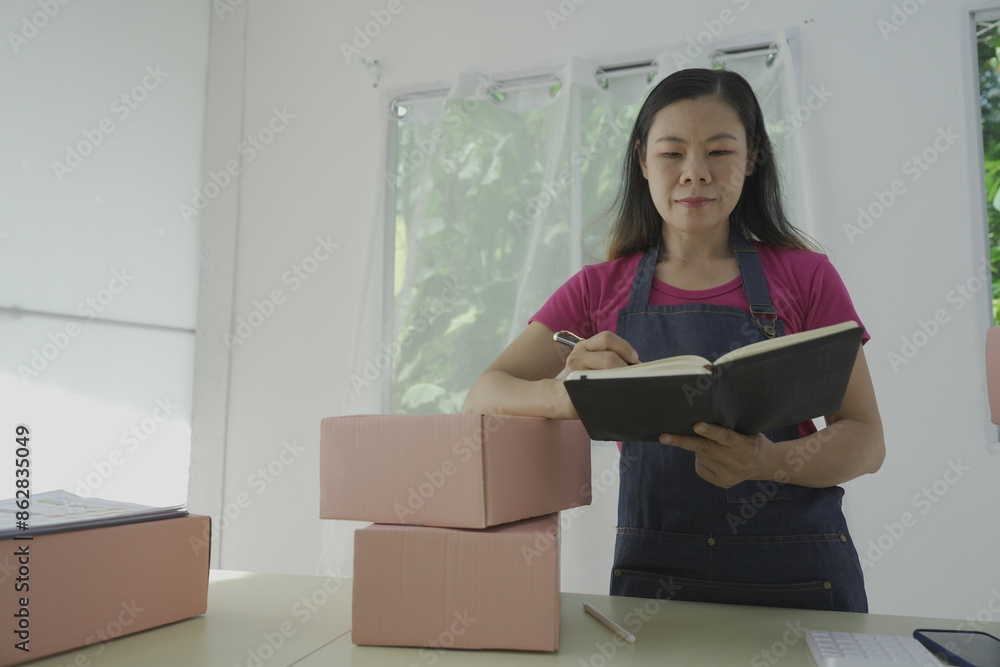Portrait of Asian woman, freelance e-commerce worker with parcel boxes for delivery to customers. and inspect the parcel box and the concept of sending online marketing boxes Portrait of Asian woman, freelance e-commerce worker with parcel boxes for delivery to customers. and inspect the parcel box and the concept of sending online marketing boxes