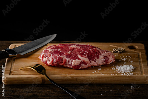 A slice of beef on a cutting board with a knife and fork