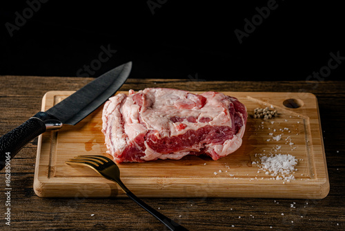 A slice of beef on a cutting board with a knife and fork