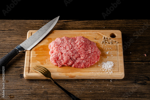 A slice of beef on a cutting board with a knife and fork