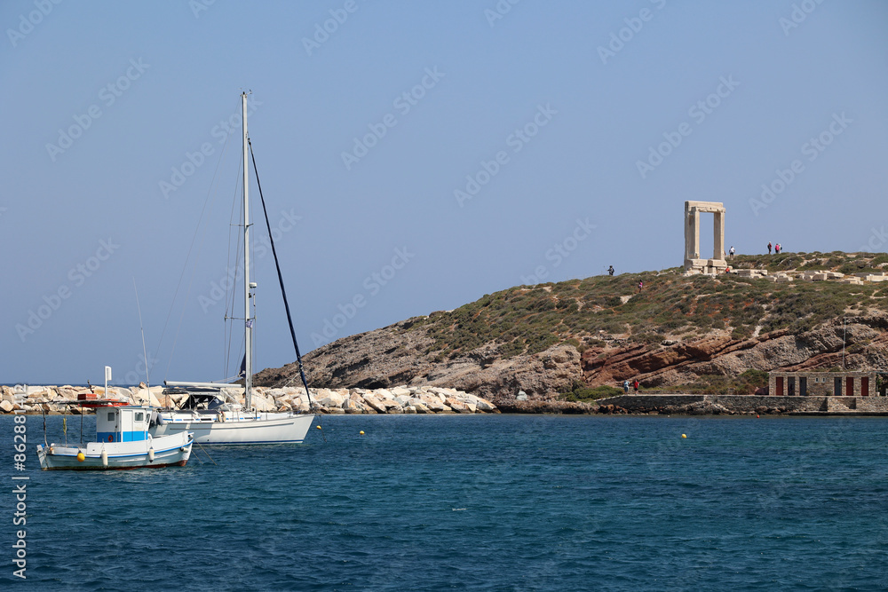 Sailboats in the port of the Cyclades island of Naxos-right fragment of the Temple of Apollo- Portara-Greece Sailboats in the port of the Cyclades island of Naxos-right fragment of the Temple of Apollo- Portara-Greece