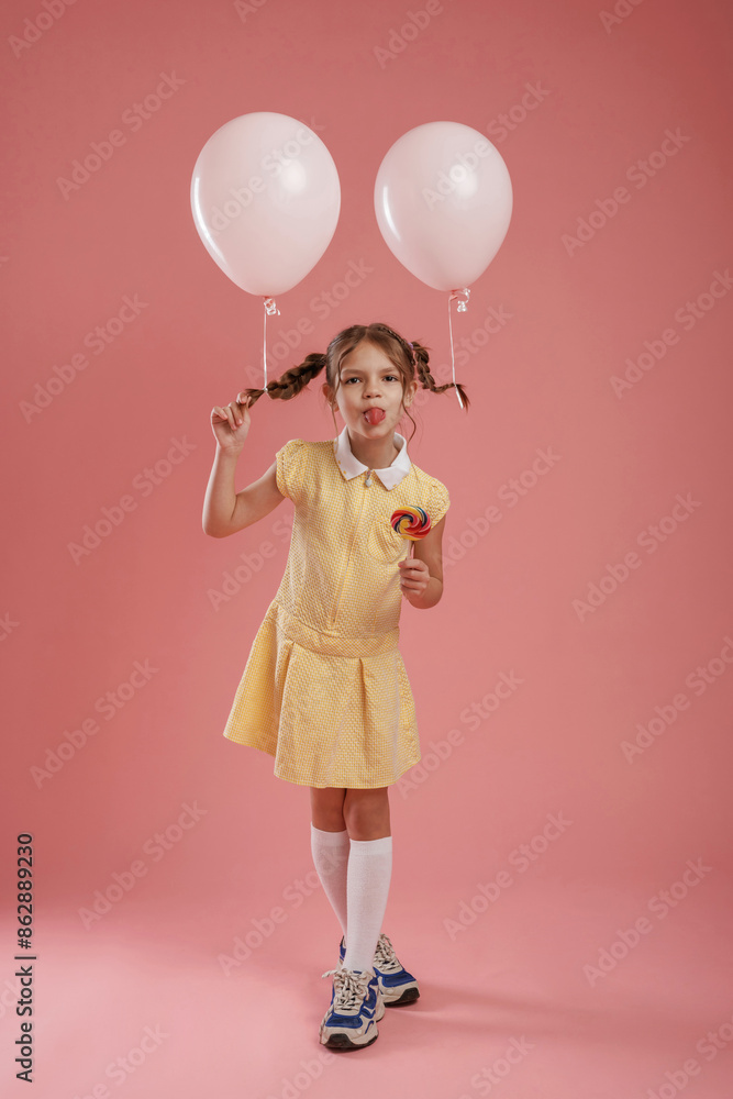 Showing tongue, playful, with balloons. Cute little girl is against pink background Showing tongue, playful, with balloons. Cute little girl is against pink background