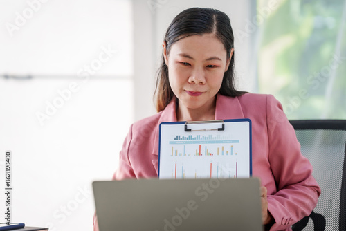 40-year-old middle-aged Asian businesswoman wearing pink suit, business finance, investment strategies, risk management. Skilled in planning, analysis, operations control for business success.