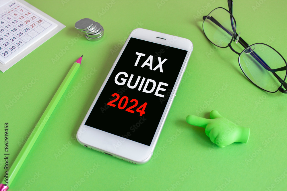 Concept red words Tax guide 2024 written on the mobile phone screen. Beautiful green background. Glasses, coins. Business concept. Concept red words Tax guide 2024 written on the mobile phone screen. Beautiful green background. Glasses, coins. Business concept.