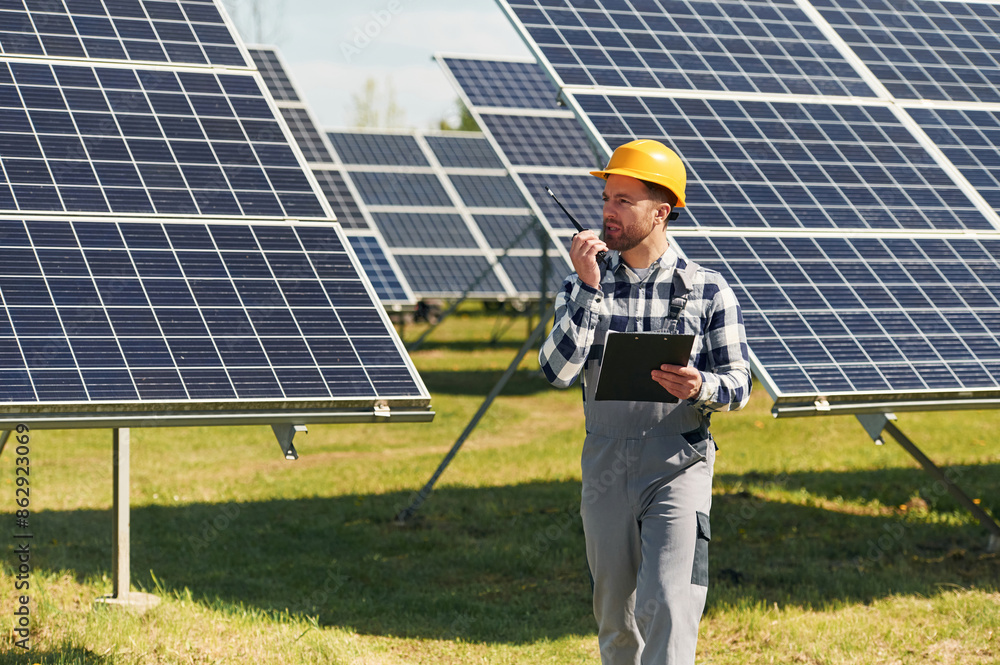Communication by using walkie talkie. Engineer with photovoltaic solar panels outdoors at daytime Communication by using walkie talkie. Engineer with photovoltaic solar panels outdoors at daytime