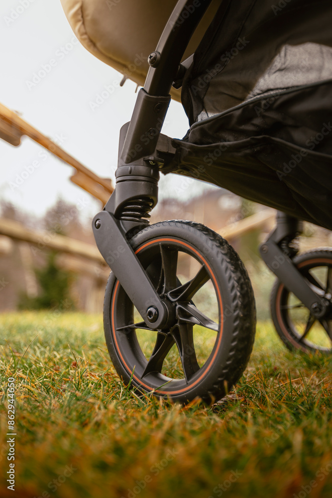 Detail on wheels of outdoor stroller on green mountain meadow in winter Detail on wheels of outdoor stroller on green mountain meadow in winter