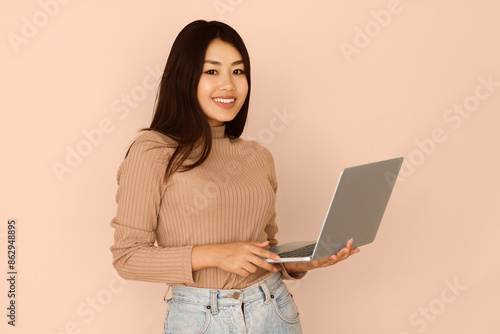 Student Girl Holding Laptop and Sending E-mail to Friend, Peach Studio Background