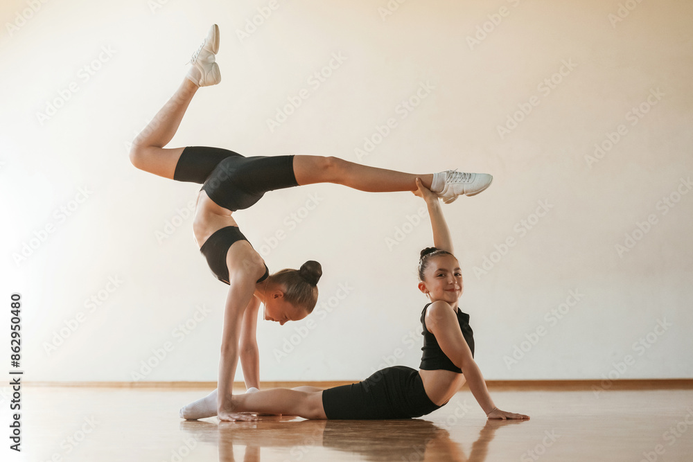 Naklejka premium Doing duo practice. Kids are doing athletic exercises indoors together