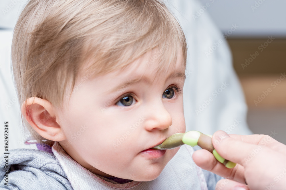 Adorable baby girl being fed with a spoon Adorable baby girl being fed with a spoon