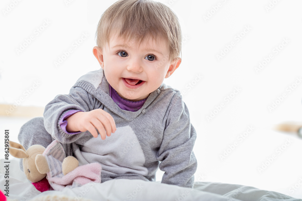 Fototapeta premium Adorable baby girl playing on bed with stuffed animal