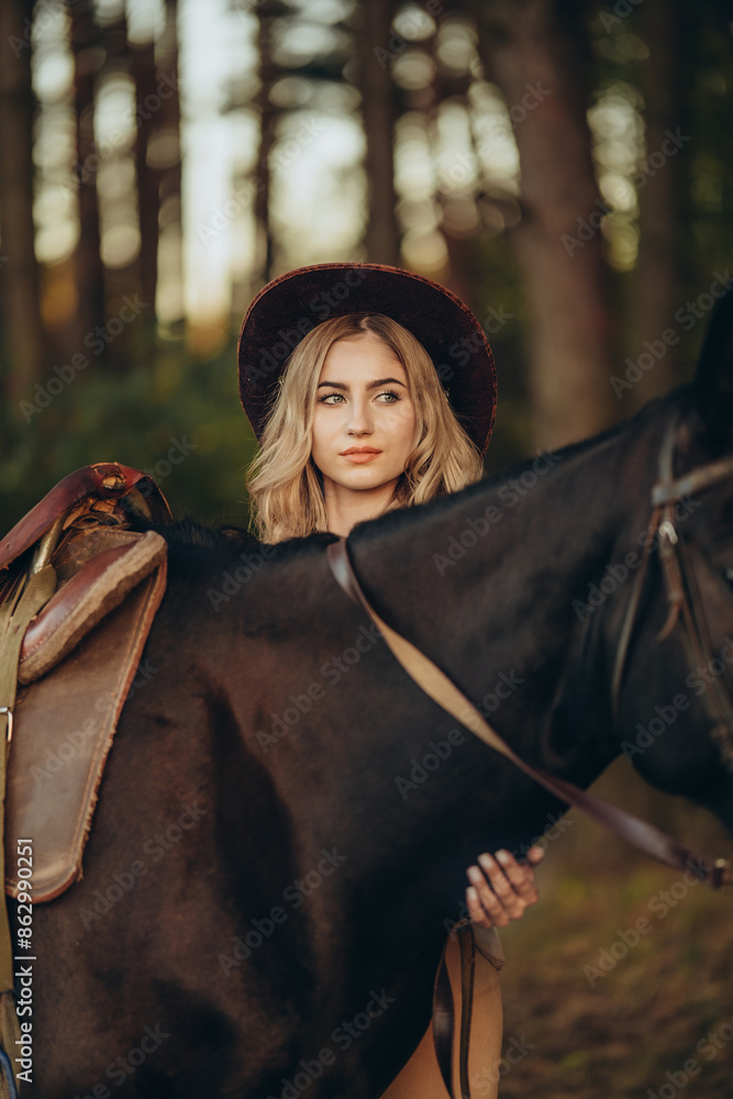 Naklejka premium A young beautiful woman walks with her horse in the forest in early autumn. Walking with a horse in the forest.