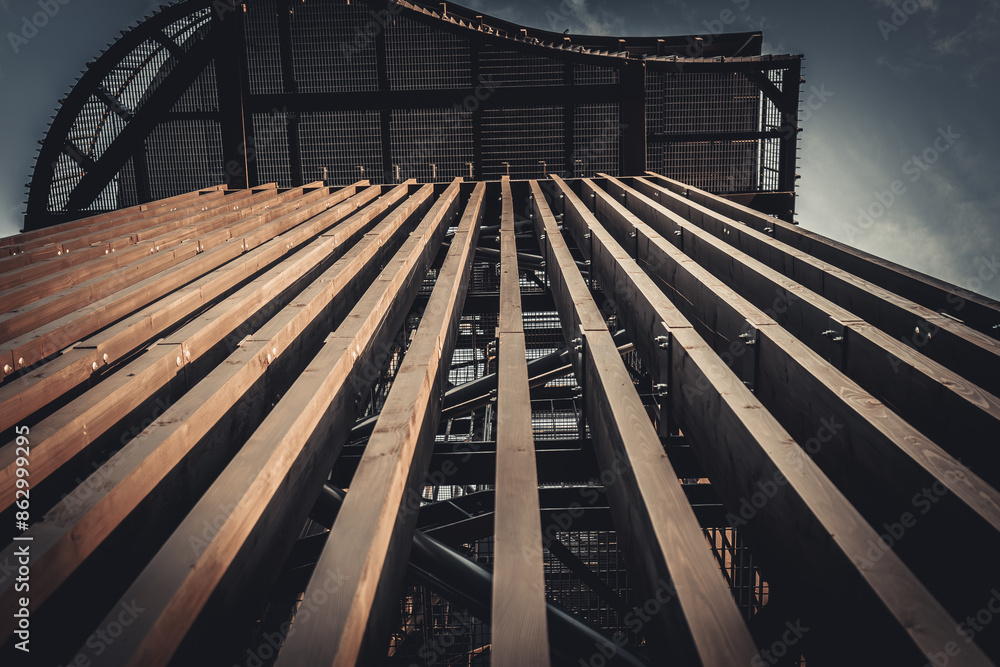 A close-up view of a metal staircase inside an industrial structure, with light filtering through the railings. The geometric design and shadows create an intriguing visual. A close-up view of a metal staircase inside an industrial structure, with light filtering through the railings. The geometric design and shadows create an intriguing visual.