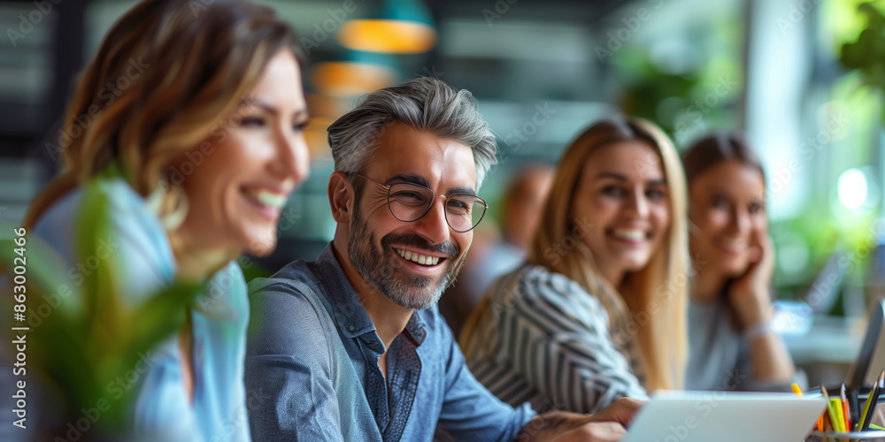 Obraz premium Smiling business people having a discussion in an office crowded around a laptop 
