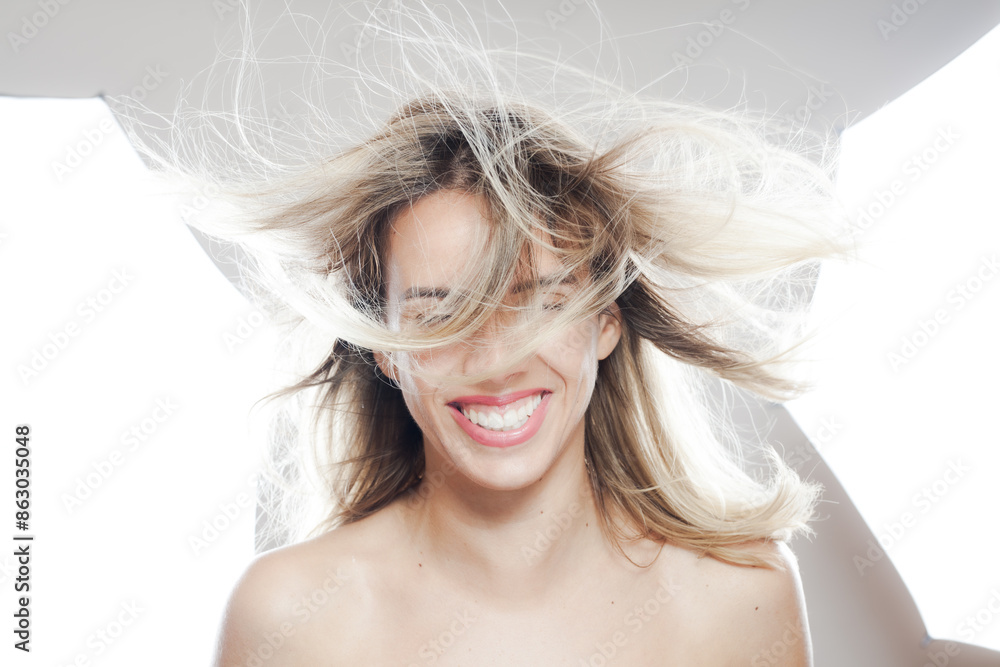 Joyful young woman with flowing hair and bright smile against a white backdrop Joyful young woman with flowing hair and bright smile against a white backdrop