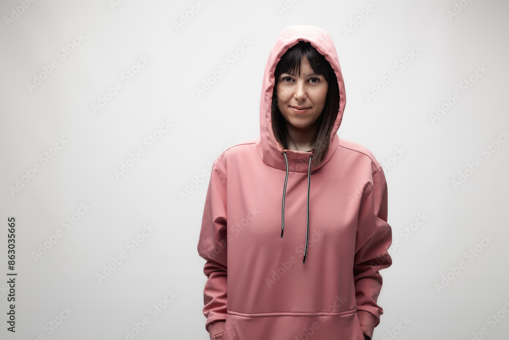 Portrait of a confident young woman in a pink hoodie, standing against a neutral background Portrait of a confident young woman in a pink hoodie, standing against a neutral background